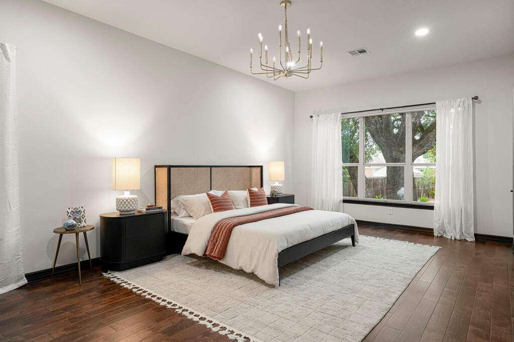 Hardwood floors and a large window define this bedroom, offering ample light and a comfortable ambiance.