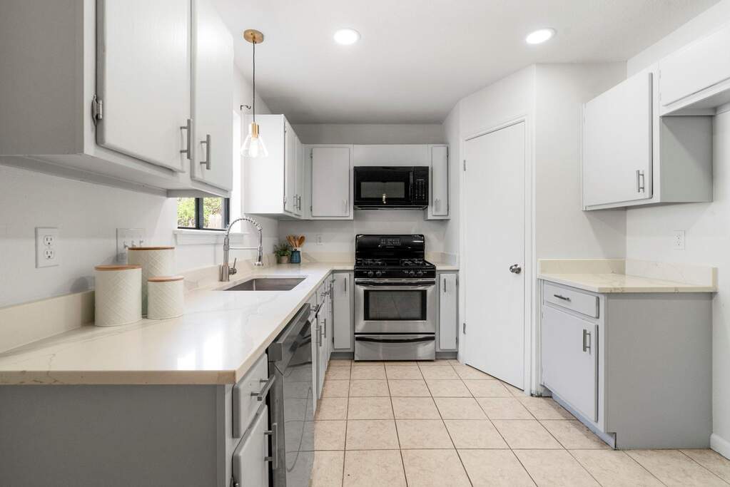 Kitchen featuring stainless steel appliances, light stone counters, pendant lighting, and gray cabinetry