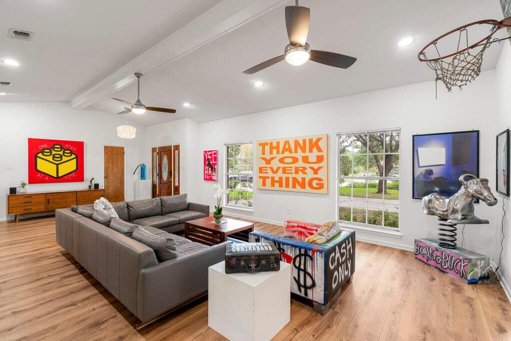 An inviting gathering space features warm wood flooring and abundant natural light from multiple large windows.