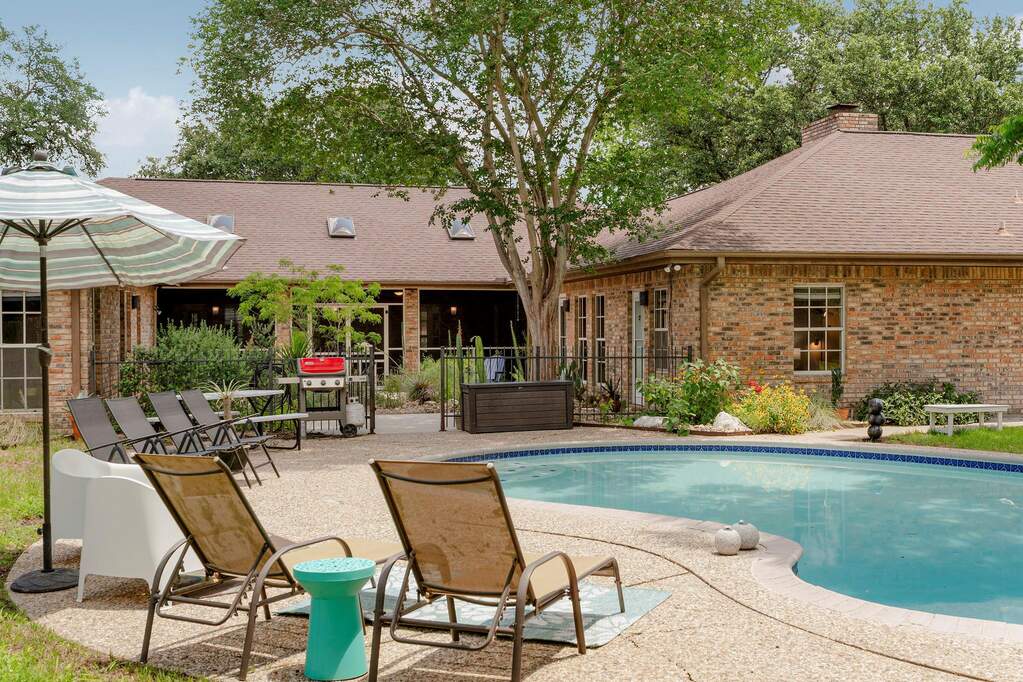 A private backyard oasis features a free-form pool, ample patio space, and mature landscaping.