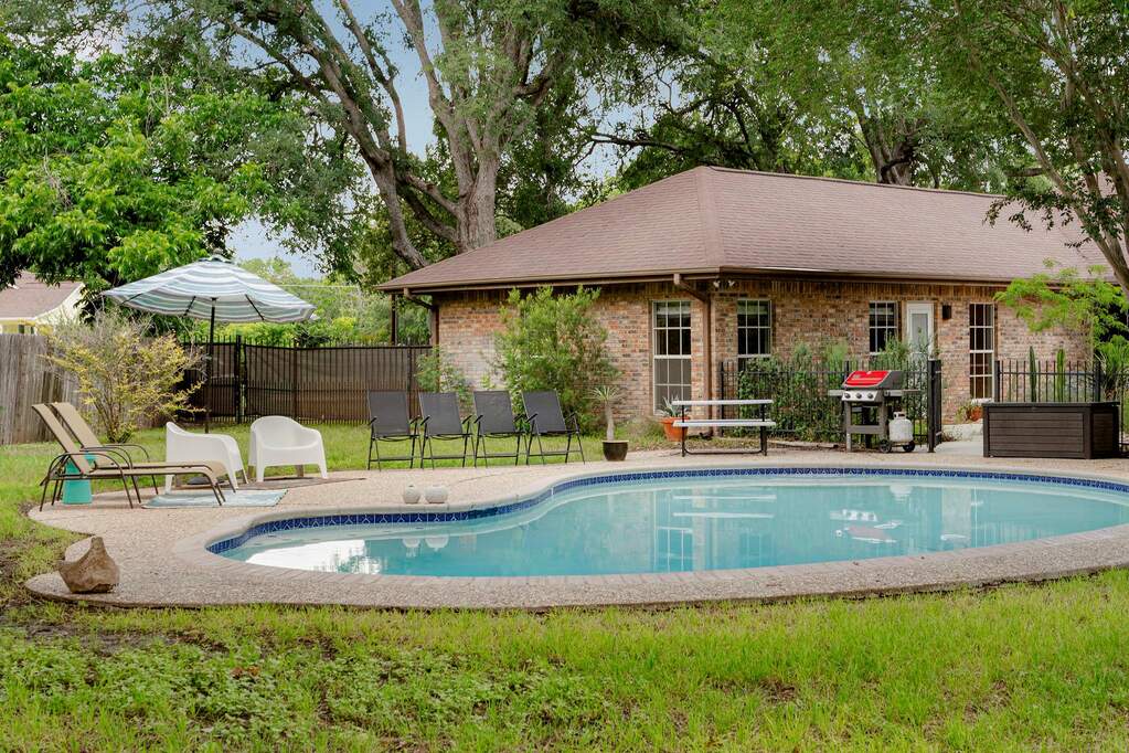 An inviting backyard oasis awaits with a sparkling inground pool and brick home.