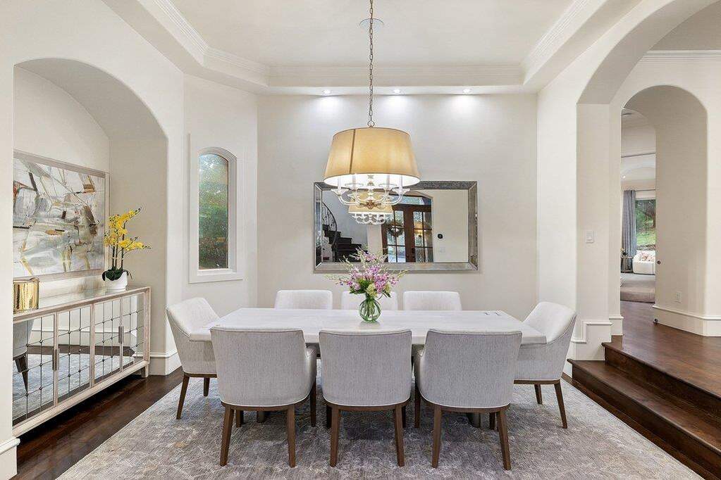 Bathed in the soft glow of a designer statement pendant, this formal dining enclave epitomizes the 'Hill Country Modern' aesthetic.