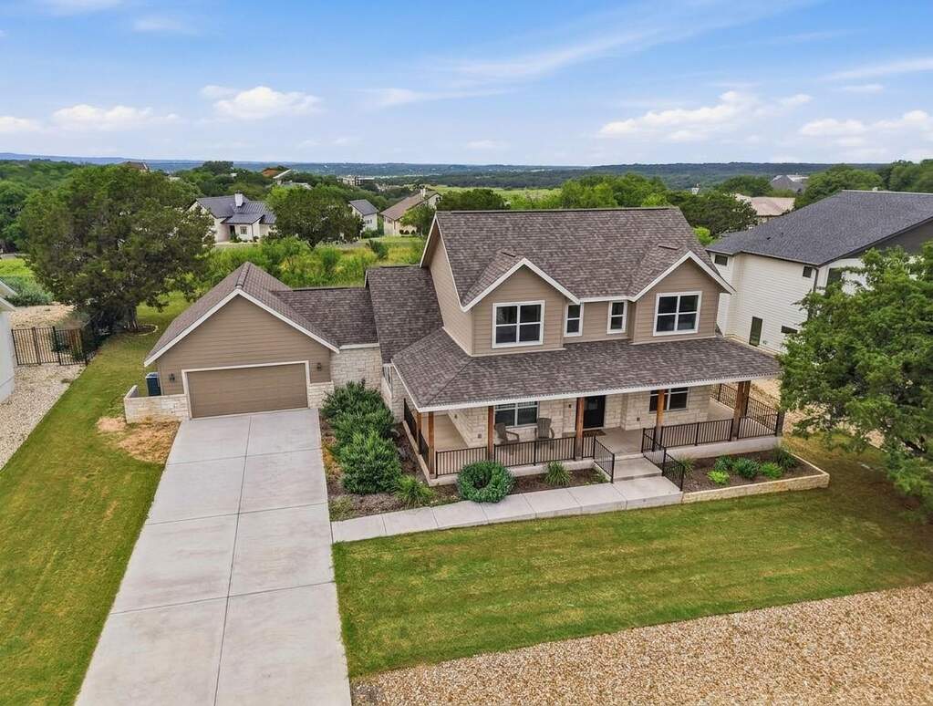 Two-story residence featuring a covered front porch with dark railings and natural wood columns