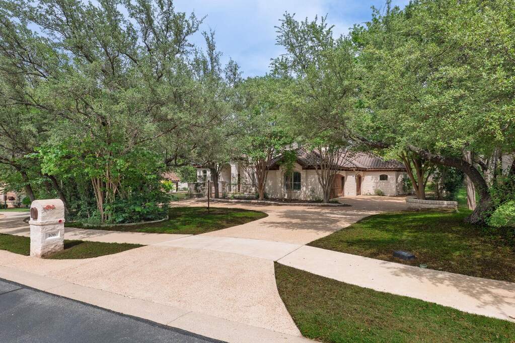 Graceful curb appeal with a sweeping drive, natural landscaping, and elegant architectural details.