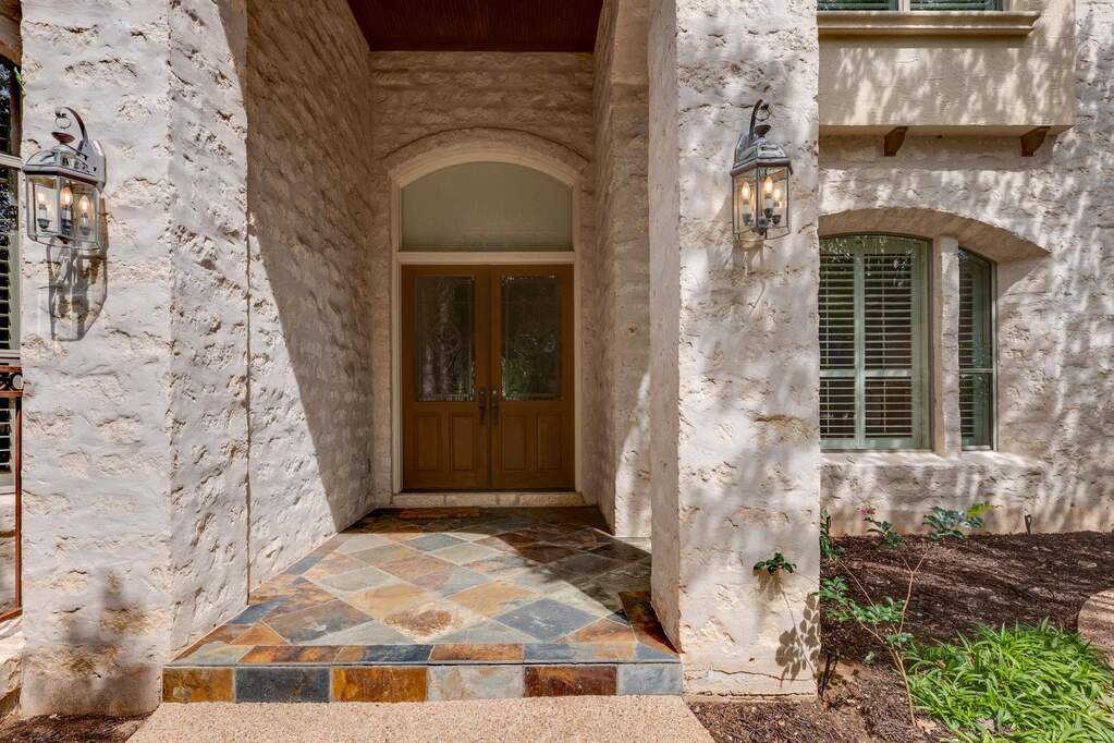 Covered front entry with stone details, double wood doors, and timeless architectural character.