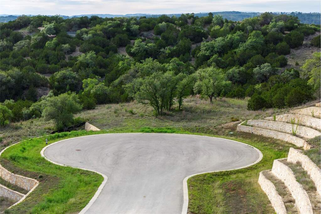 Cul-de-sac lot with terraced stone retaining walls, mature trees, and natural landscaping