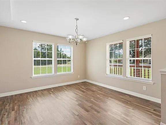 Empty room with a chandelier, wood finished floors, and recessed lighting