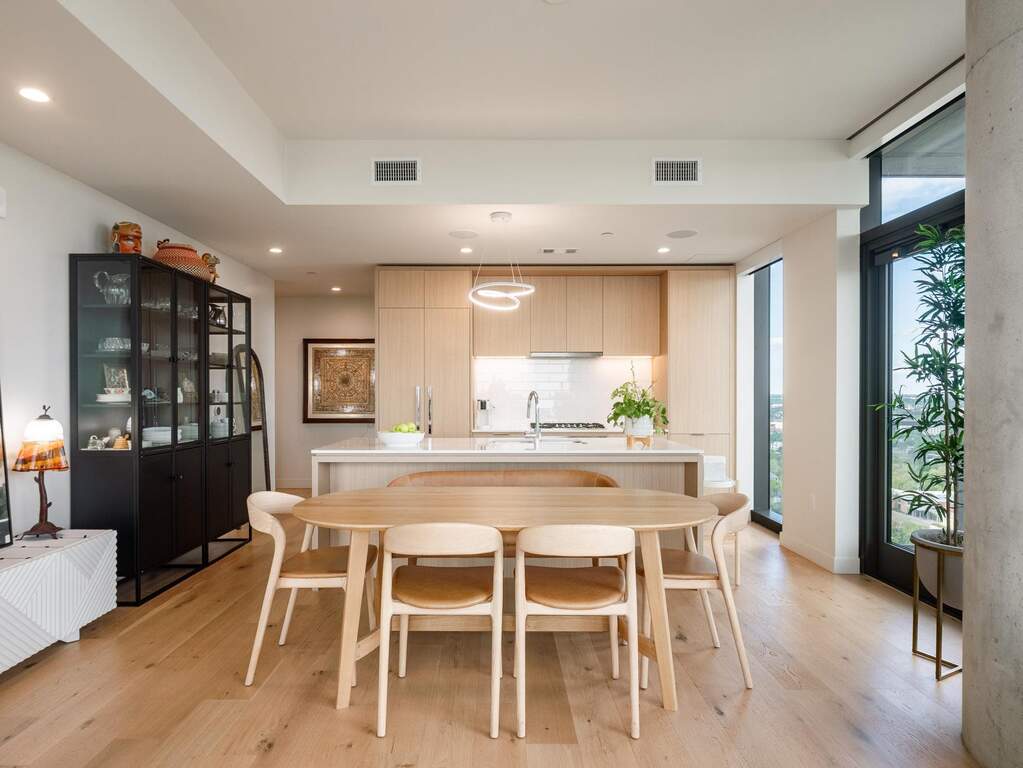 The open concept living area features hardwood floors, a kitchen with light wood cabinetry, and large windows that provide abundant natural light