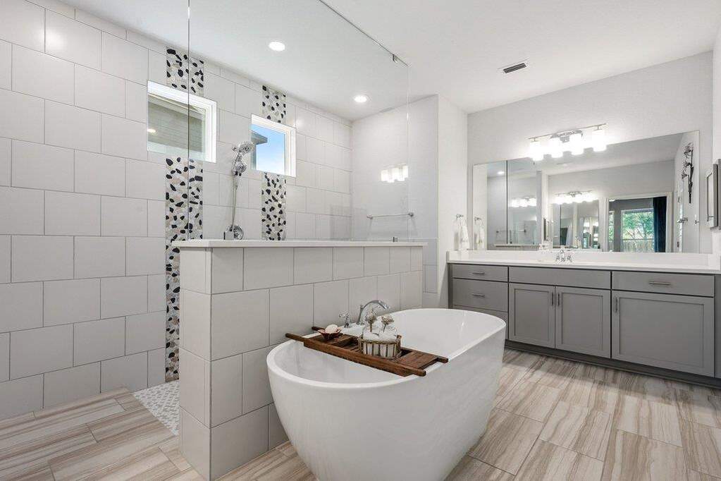 Freestanding soaking tub, walk-through shower and separate vanities on opposite sides.