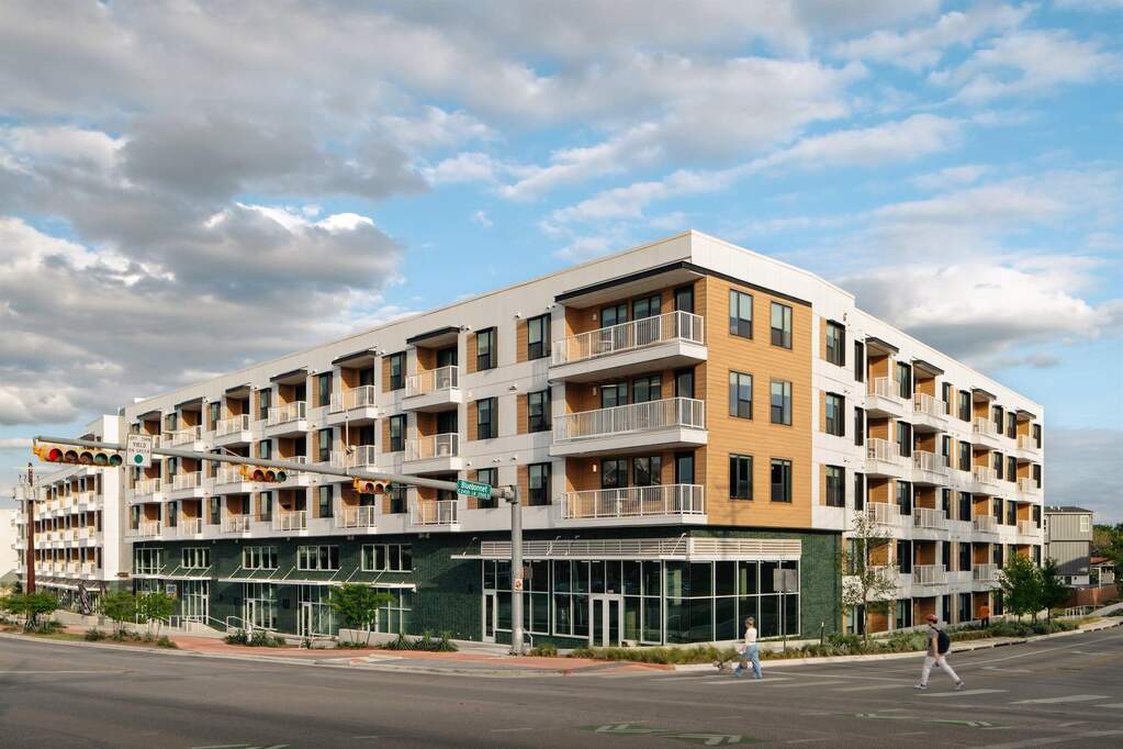 The southwest corner of The Code highlights the building’s design by STG Design, featuring green tile accent balconies and ground floor retail dedicated to health, wellness, and dining. A mod