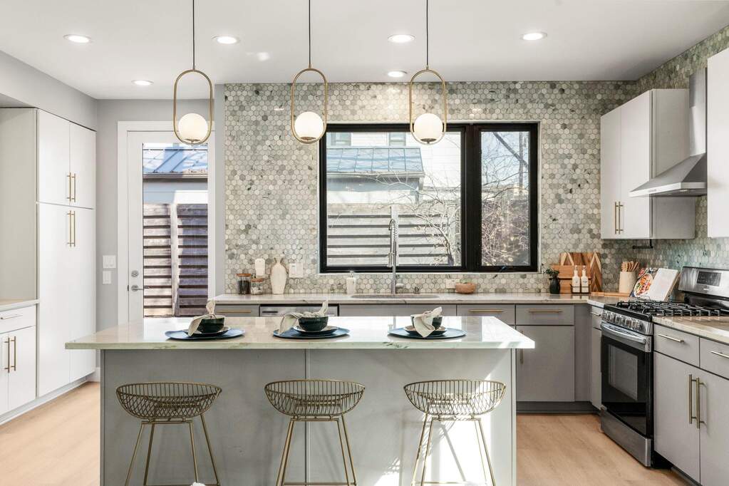 A chef-forward kitchen anchors the main level with a large island, sleek cabinetry, and statement lighting.