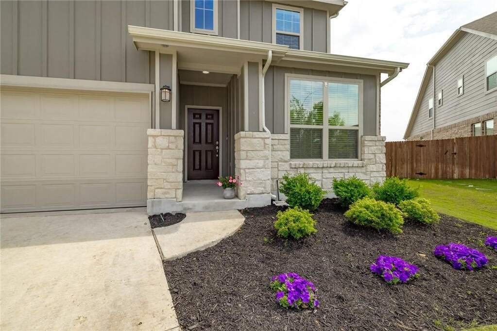 Contemporary exterior featuring board and batten siding, stone veneer accents, and a covered entry