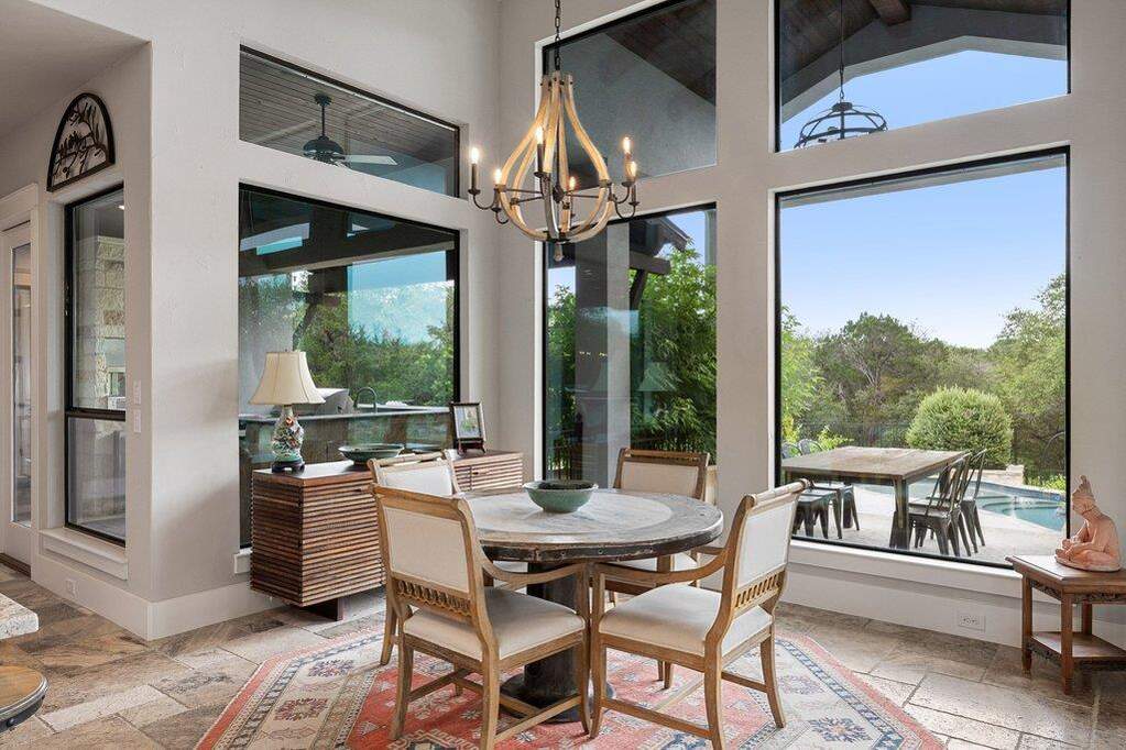 Beautiful vignette in the breakfast nook, with a perfectly sized octagonal rug, chandelier and floor to ceiling windows looking out to the pool.