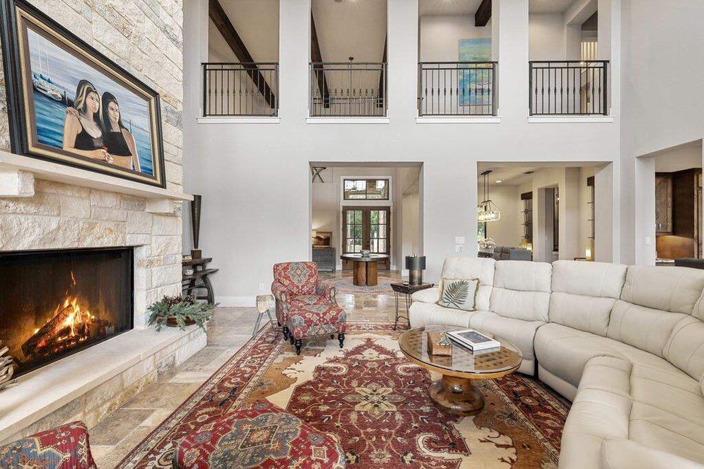 A grand living space with towering ceilings and a captivating stone fireplace, perfect for elegant gatherings. View here is of the upstairs catwalk leading from the grand staircase to the bed