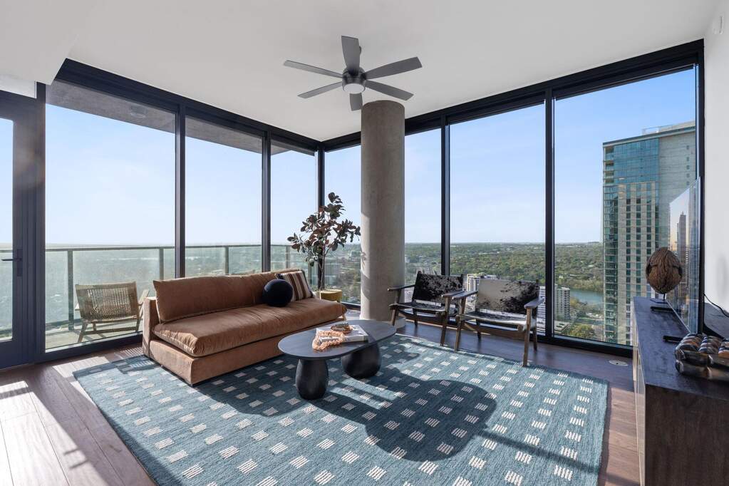 Representative Photo. Open Concept living room with hardwood flooring, floor to ceiling windows, recessed lighting, ceiling fan, and a balcony off the living room with a South East view