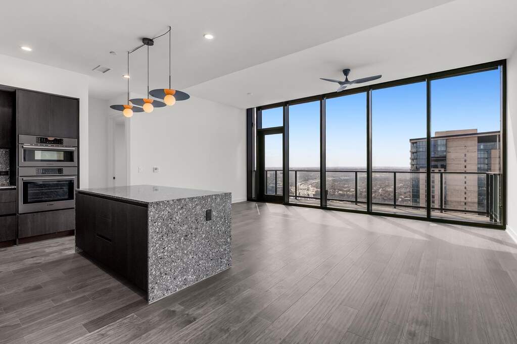Open Concept living room with 7.5" wide Bella Cera hardwood flooring, recessed lighting, ceiling fan, and a balcony off the living room with a stunning South view