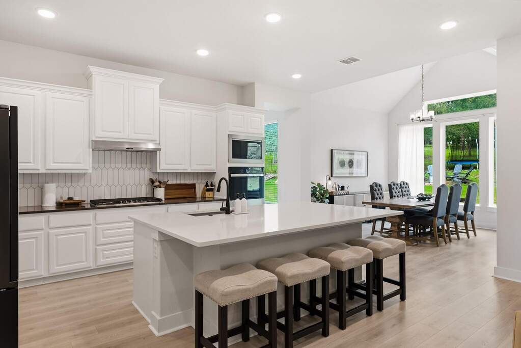 The gorgeous kitchen is a chef’s dream, featuring quartz countertops, a tile backsplash, and a large center island that invites everyone to gather around