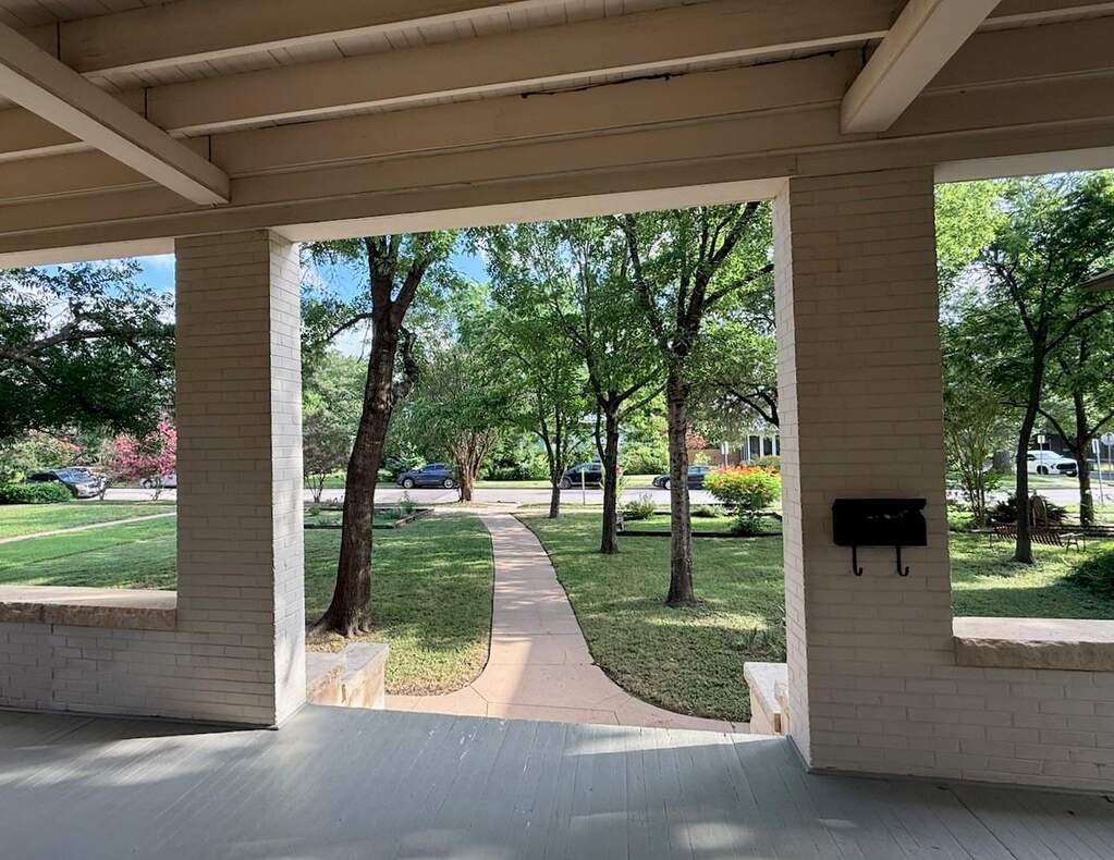 An inviting front porch offers peaceful views of the landscaped yard and tree-lined street.