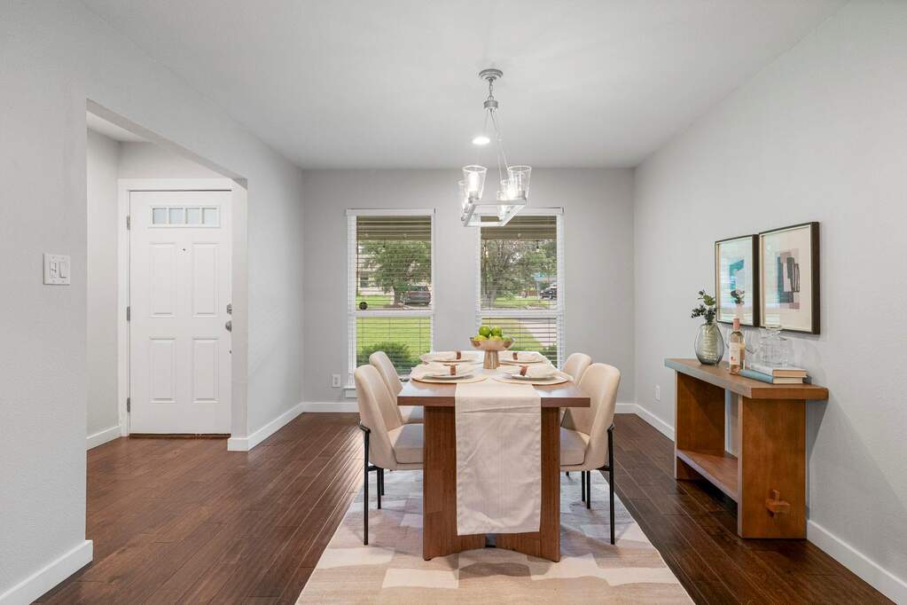 Dining area with updated lighting, rich hardwood floors, and oversized windows creating a bright and welcoming setting for entertaining