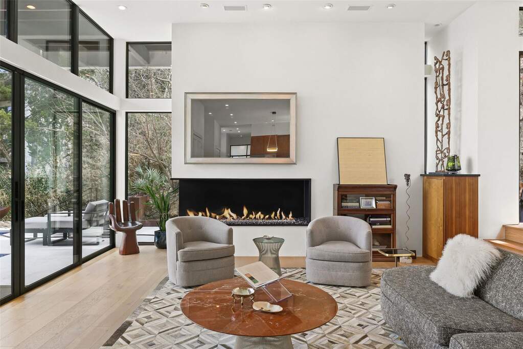 Modern living space featuring a linear fireplace, light wood-finish flooring, and recessed ceiling lighting