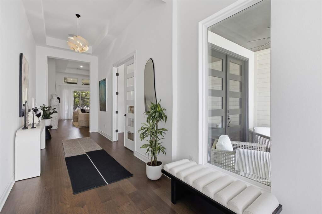 Wide entry hall with dark hardwood floors, tray ceiling, statement pendant light.