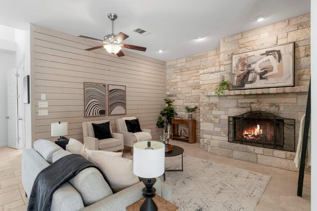 Imagine relaxing in this living area! You’ve got the floor-to-ceiling stone fireplace on one side and a beautiful horizontal shiplap accent wall on the other. It’s the perfect spot to cozy up