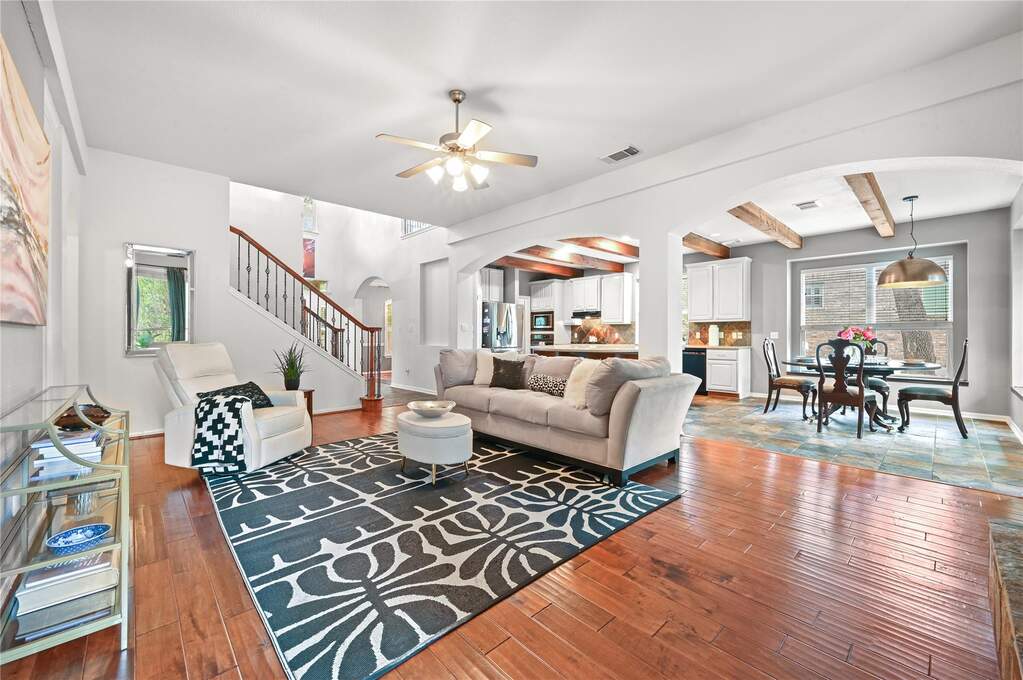 Expansive living space featuring rich wood-finish flooring and a ceiling fan