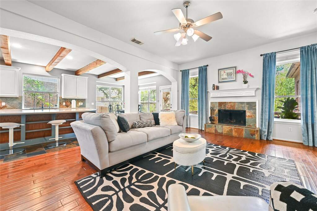 Spacious living area featuring rich wood-finish flooring and a ceiling fan