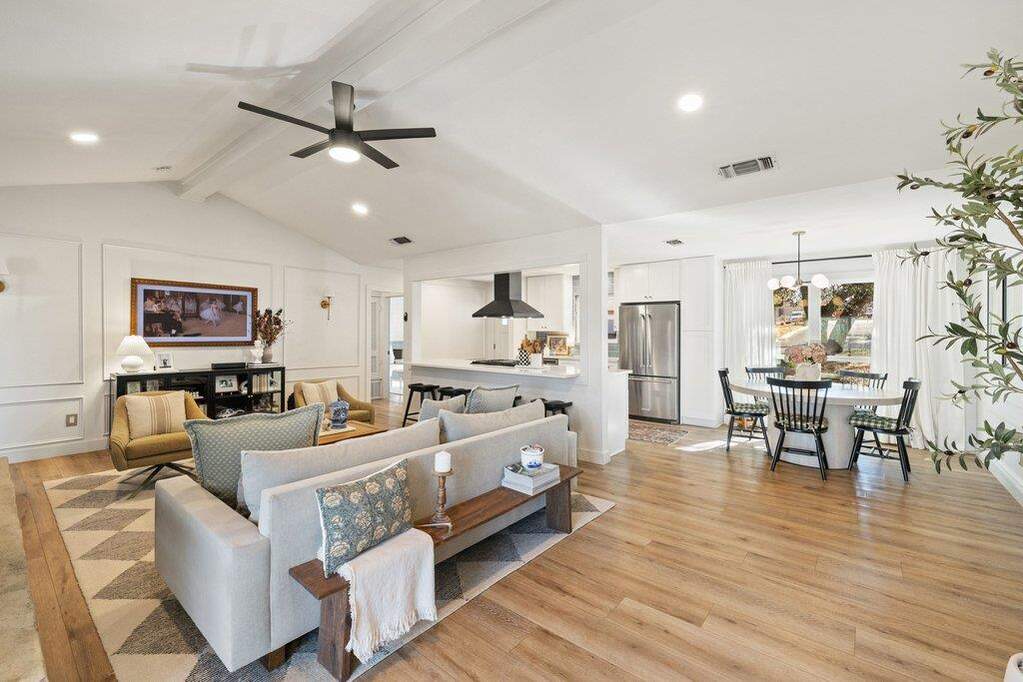 In the living room, soaring beamed ceilings, a stunning fireplace, and picture-frame moulding add architectural interest