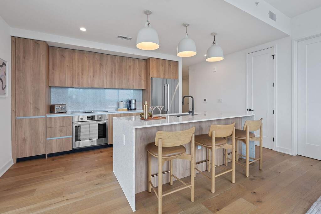 Representative Photo. Kitchen featuring custom Italkraft cabninetry, terrazzo backsplash, waterfall-edge terrazzo countertops, stainless steel Bosch appliances, and pendant lighting above kit