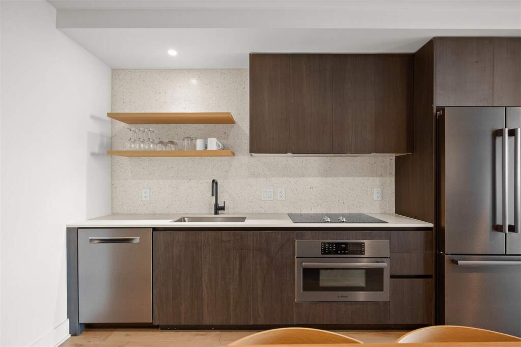 The quartz countertops shine alongside modern cabinetry, with open shelving adding an effortlessly chic touch, perfect for showcasing your favorite kitchen essentials