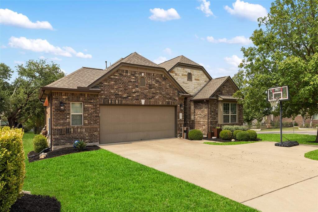 View of front of home with roof with shingles, a front yard, brick siding, an attached garage, and driveway