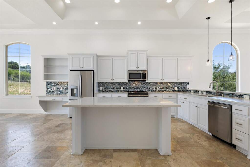 Kitchen with recessed lighting, white cabinets, decorative backsplash, stainless steel appliances, and a raised ceiling