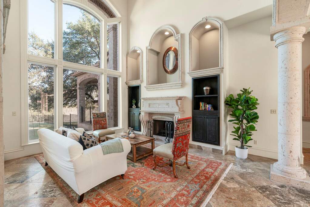 Living room with ornate columns, a high ceiling, a fireplace, and stone tile flooring