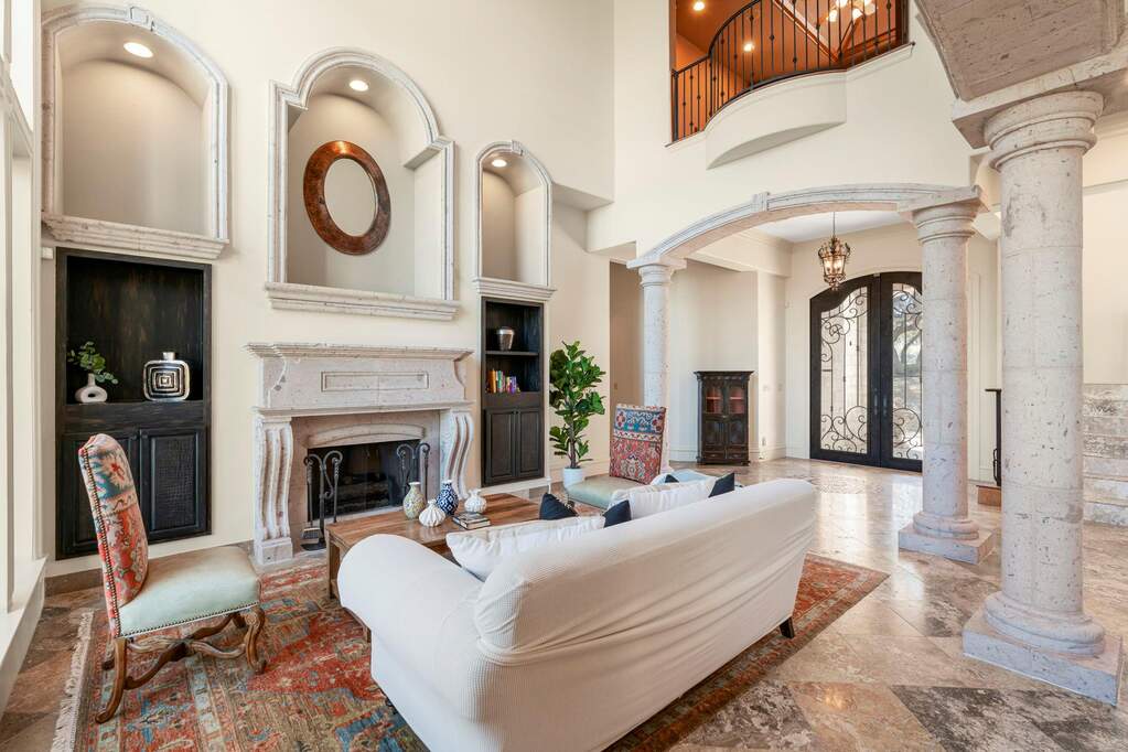 Living room with arched walkways, decorative columns, french doors, a high ceiling, and a fireplace
