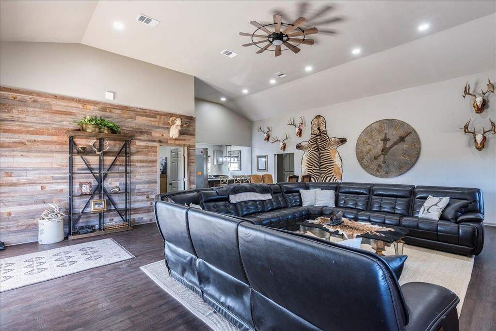 Living room with a ceiling fan, high ceiling, recessed lighting, accent wall