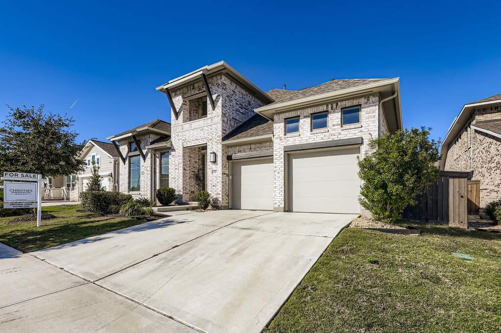 French country style house with a garage, concrete driveway, brick siding, and a front yard