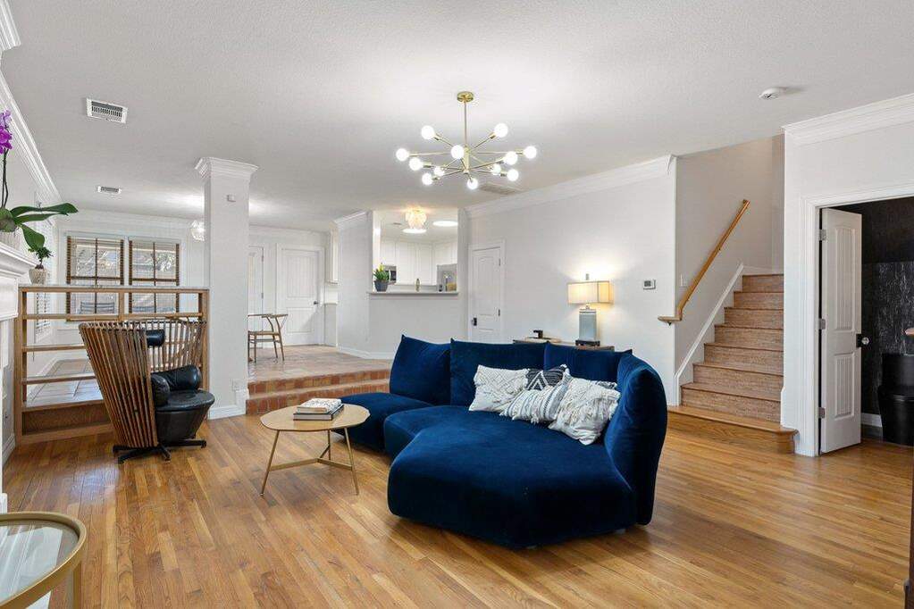 Living room featuring light wood-style flooring, ornamental molding, and a chandelier
