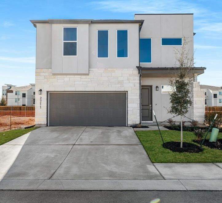 Contemporary two-story exterior featuring a light stone facade and smooth stucco accents