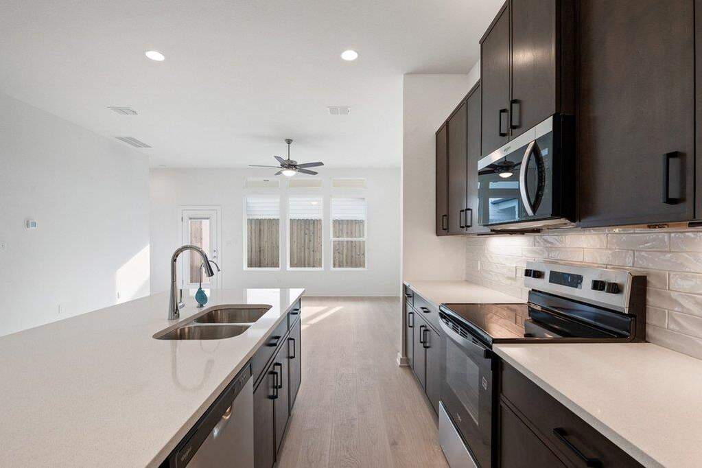 Kitchen featuring stainless steel appliances, light wood-type flooring, light stone counters, recessed lighting, and decorative backsplash