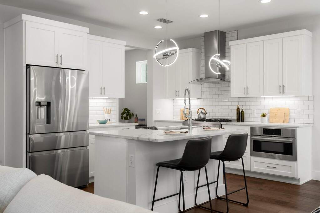 The kitchen pairs tailored cabinetry with stainless appliances—centered around the island for a polished, design-forward look.