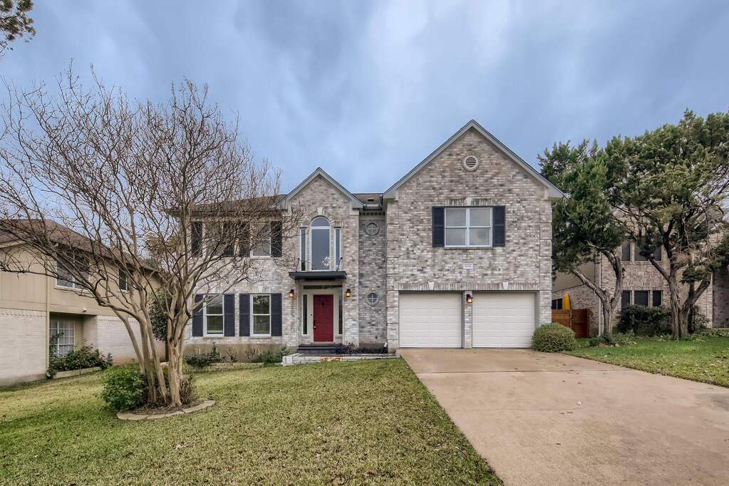 A classic brick facade with a striking red door welcomes you home, complete with an attached two-car garage.