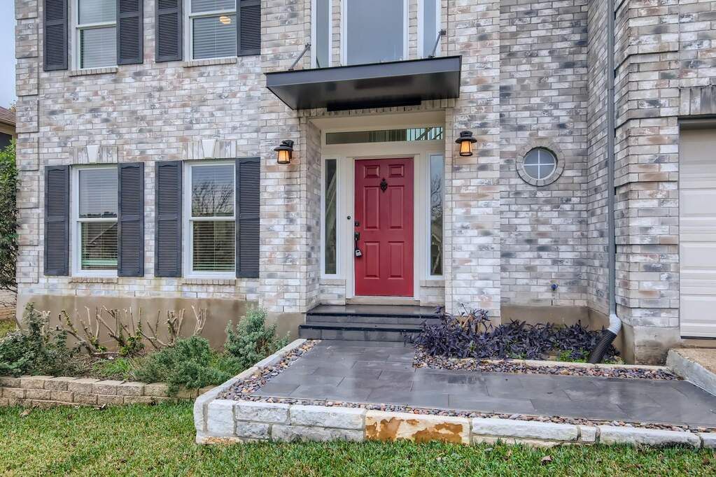 A striking red entry door welcomes guests to this distinguished brick facade home.