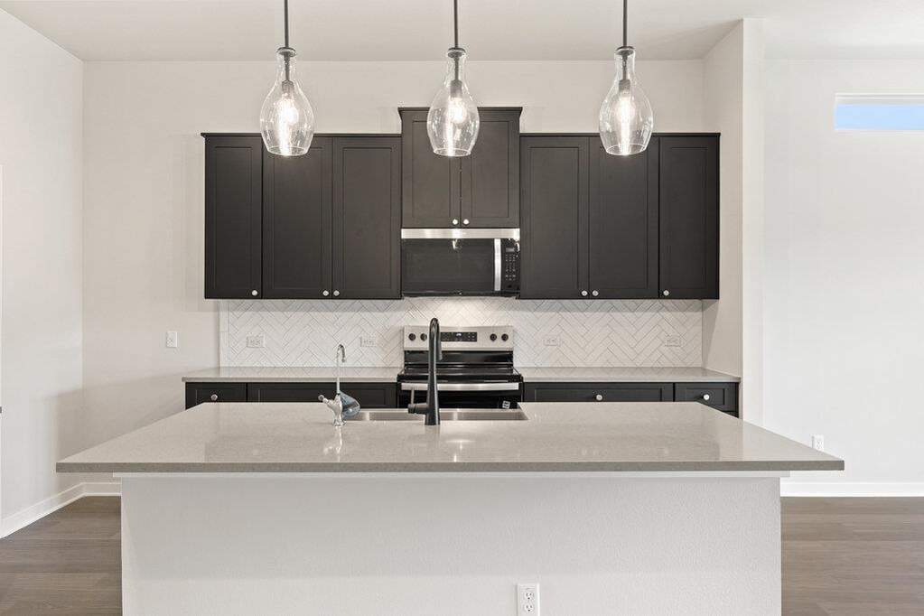 Kitchen with decorative backsplash, dark wood-style flooring, and light stone countertops