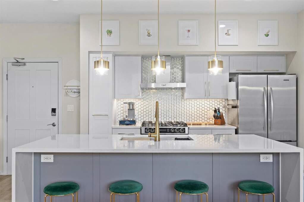 The waterfall quartz island creates a strong centerpiece, offering plenty of seating and a polished focal point for the room