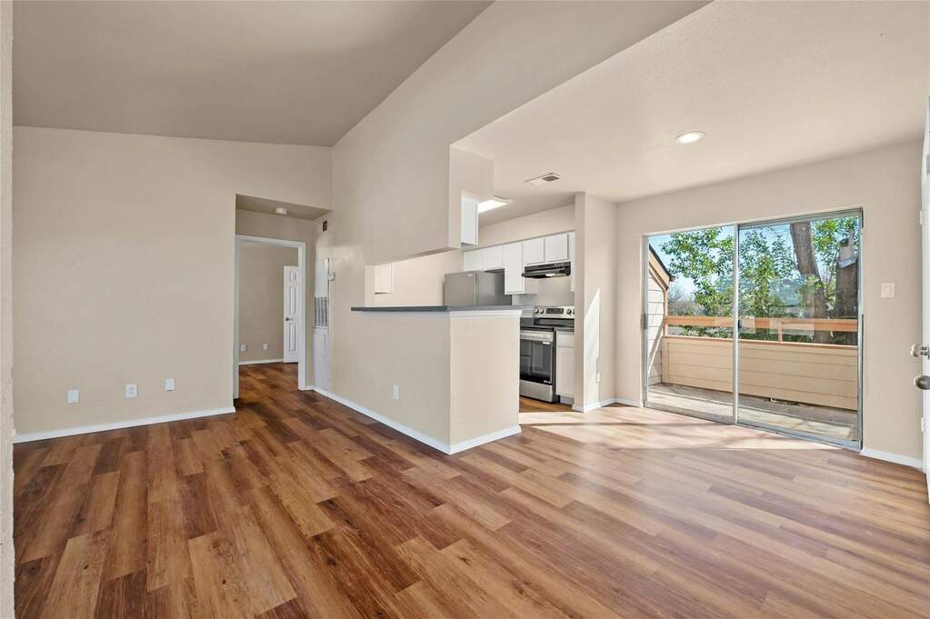 Open-concept living area featuring wood-finish flooring and ample natural light from the sliding glass door