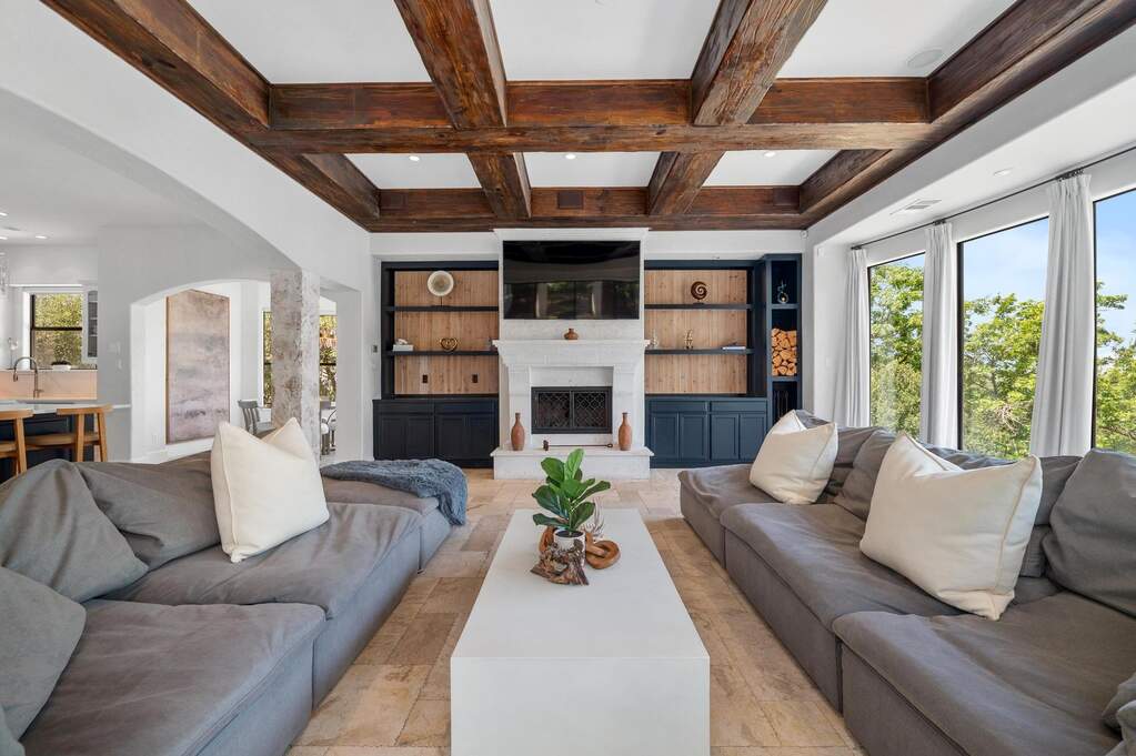 Living room fireplace, beamed ceiling, and built-in shelves