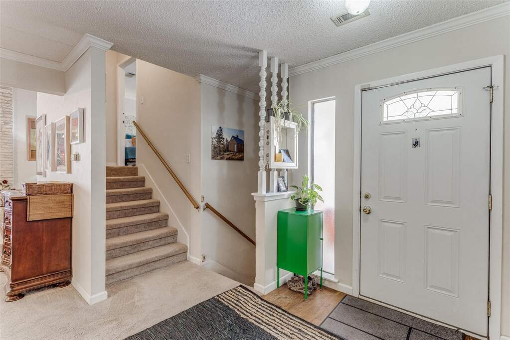 Foyer featuring ornamental molding, stairway, and a textured ceiling