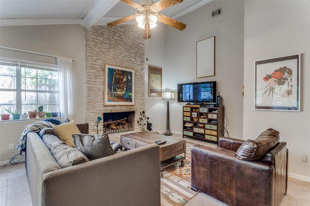 Living area with carpet floors, high vaulted ceiling, a fireplace, a ceiling fan, and crown molding