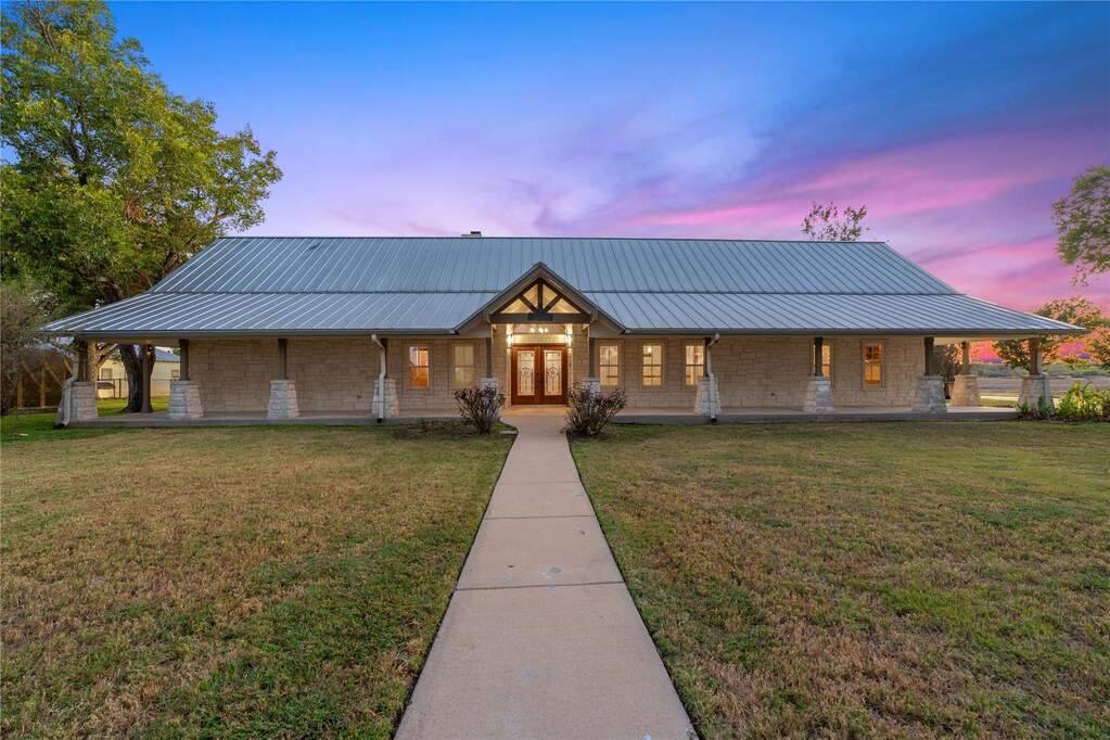 View of front of home with a front yard, a metal roof, covered porch, and french doors